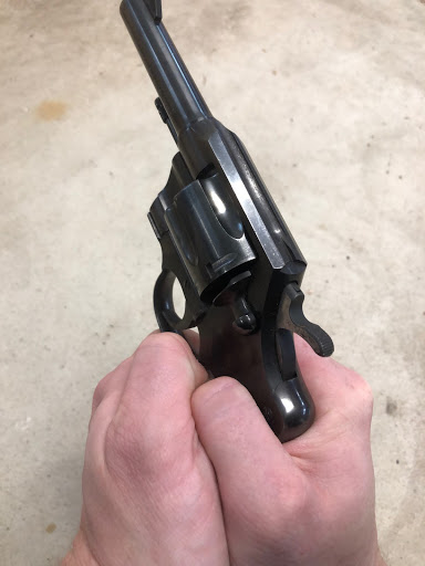 Holding a revolver with thumbs tucked.